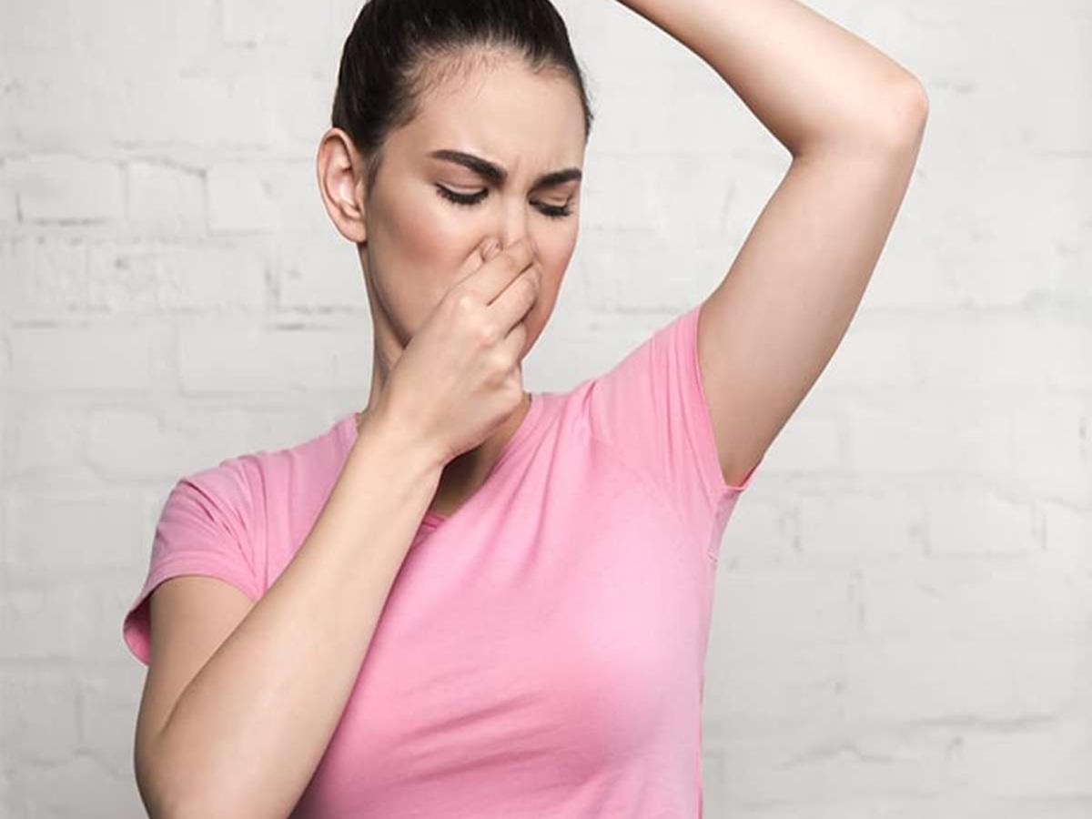 Woman smelling her shirt, concerned about body odor changes