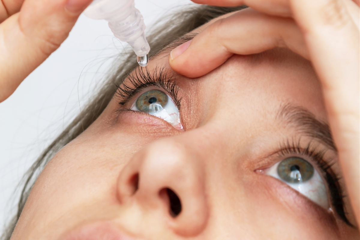Person using eye drops to relieve dryness caused by summer heat