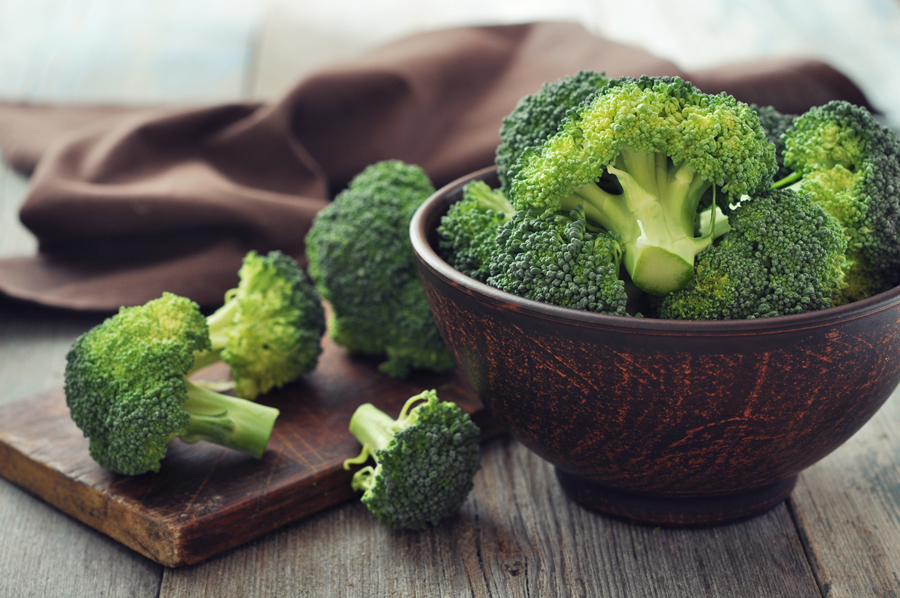 Steamed broccoli on a white plate with olive oil.