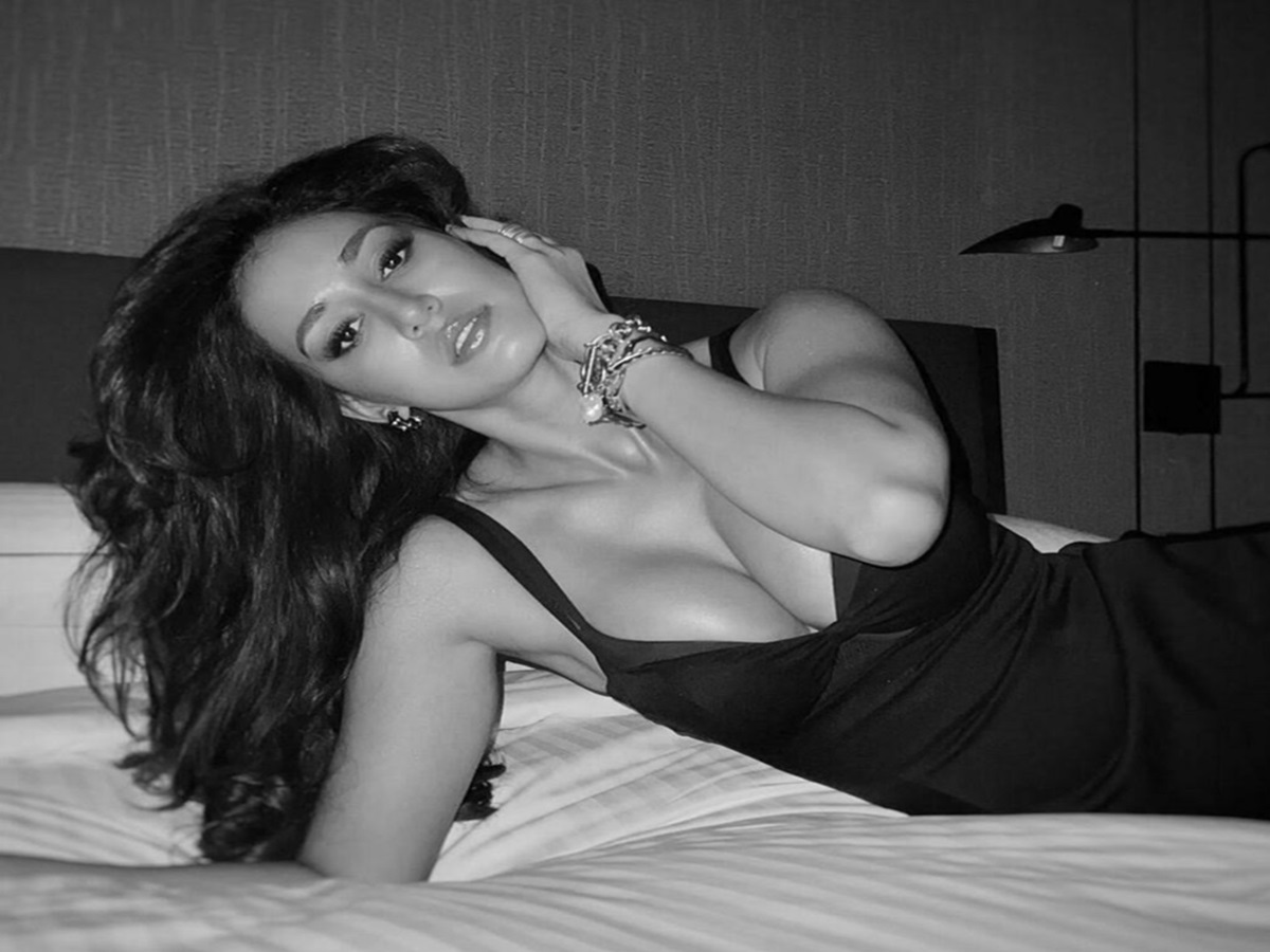 Disha Patani posing elegantly on a bed in a bright, fashion-forward bedroom setup