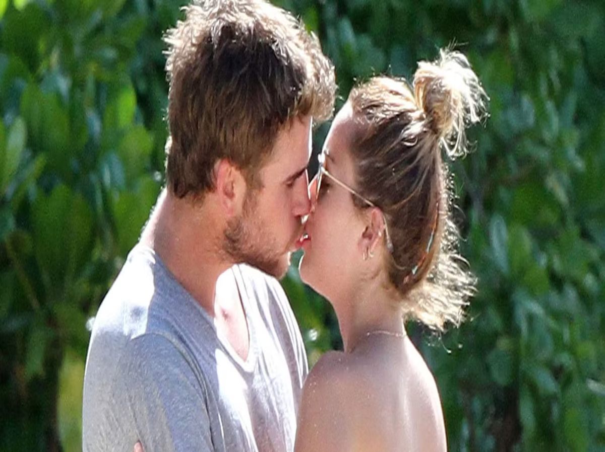 Miley Cyrus enjoying a beach day during her holiday with Liam Hemsworth, who surprises her with a kiss during lunch.