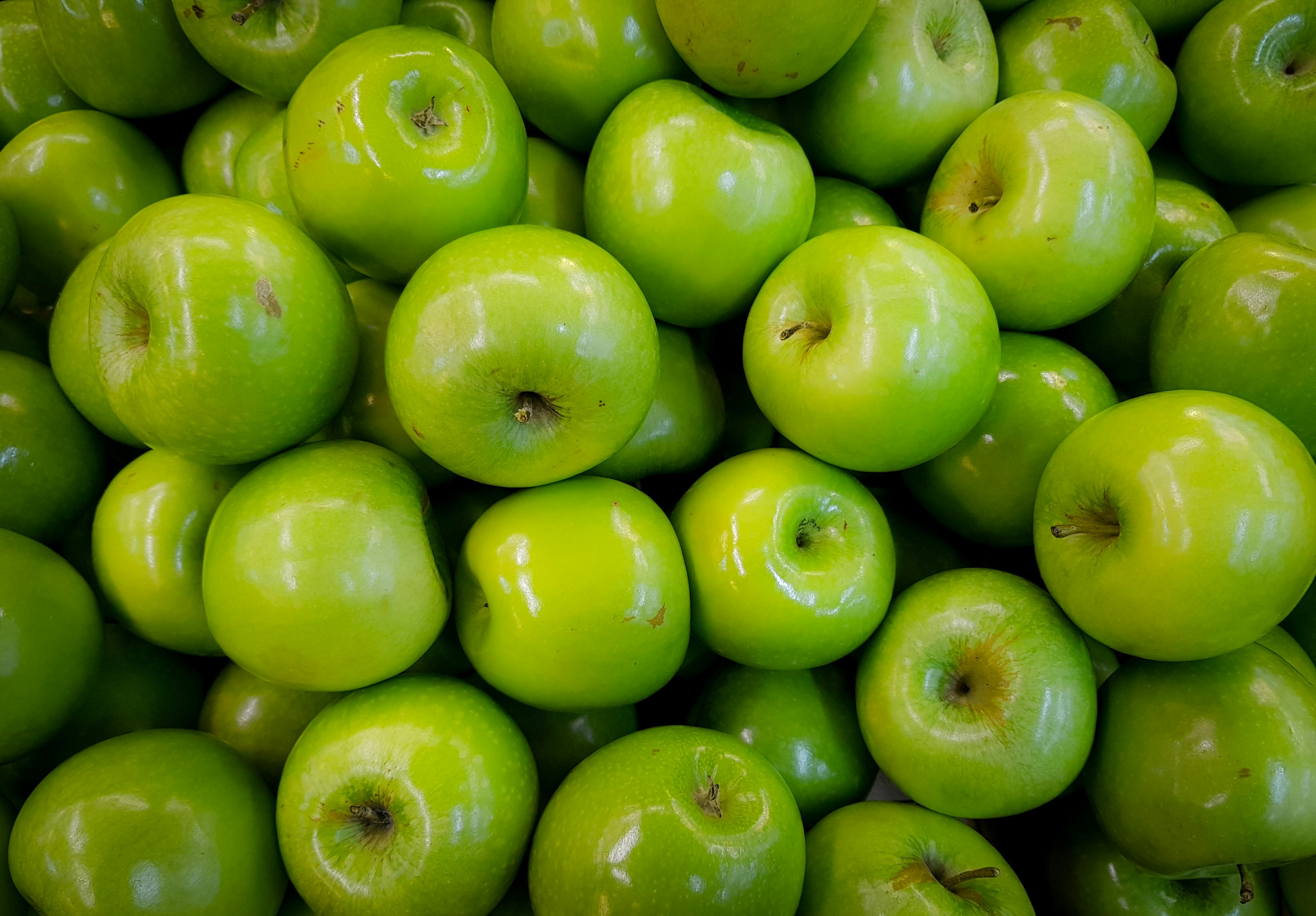 Sliced green apple with skin on a cutting board.