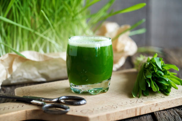 Glass of fresh wheatgrass juice with wheatgrass blades.
