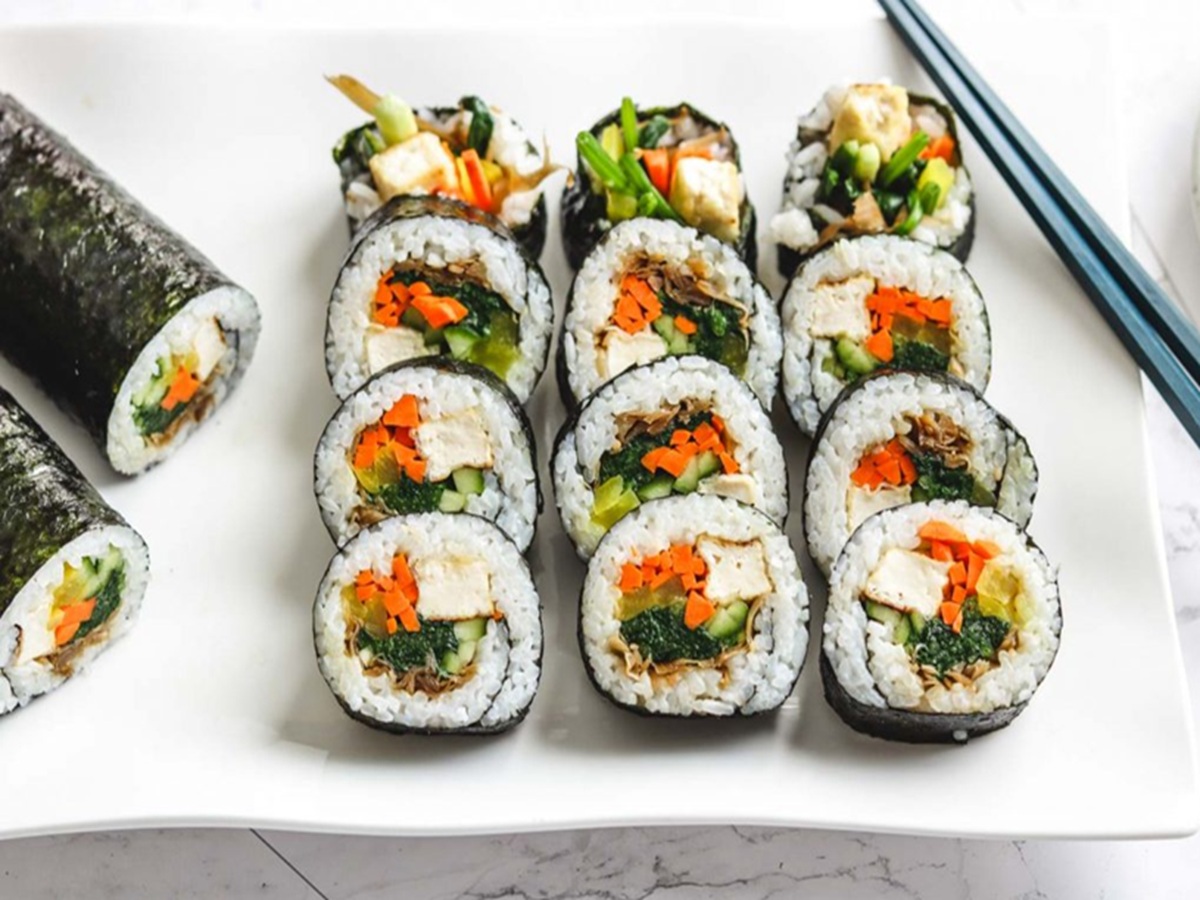 Sliced vegan kimbap rolls filled with tofu, braised burdock root, and vegetables, arranged on a plate