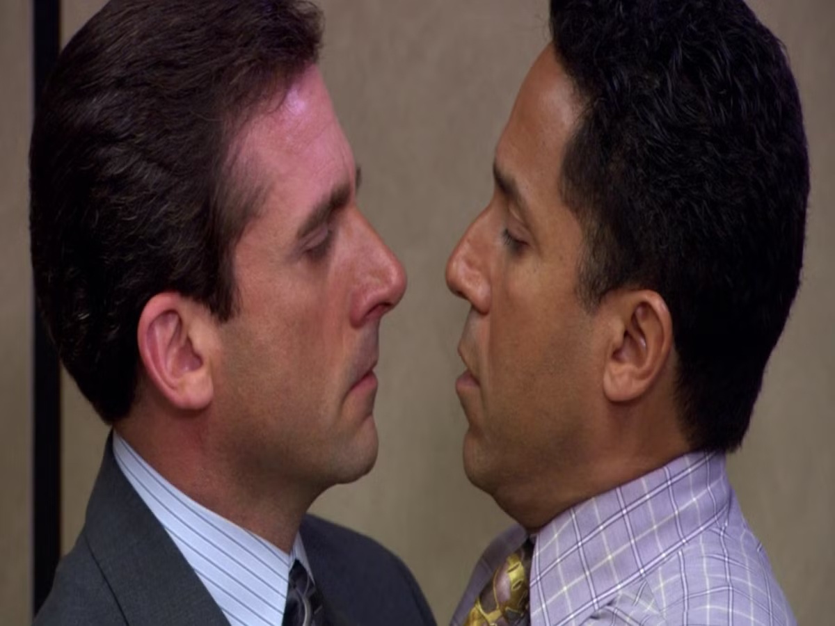 Michael Scott kissing Oscar Martinez unexpectedly in "The Office," showcasing a humorous and awkward moment that reflects the show's unique blend of comedy and poignant themes.