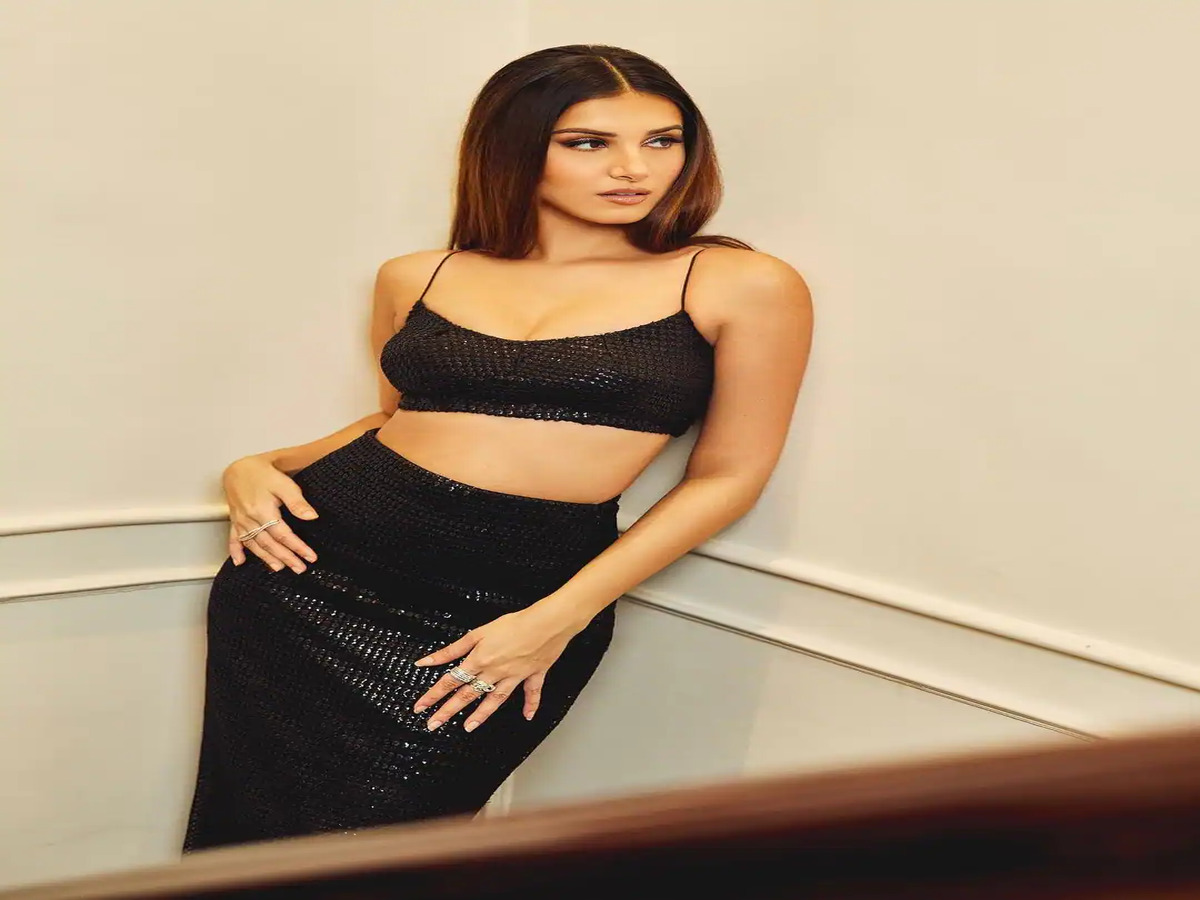 Model showcasing a sleek black crop top and high-waisted skirt, embodying contemporary fashion with a touch of glamour.