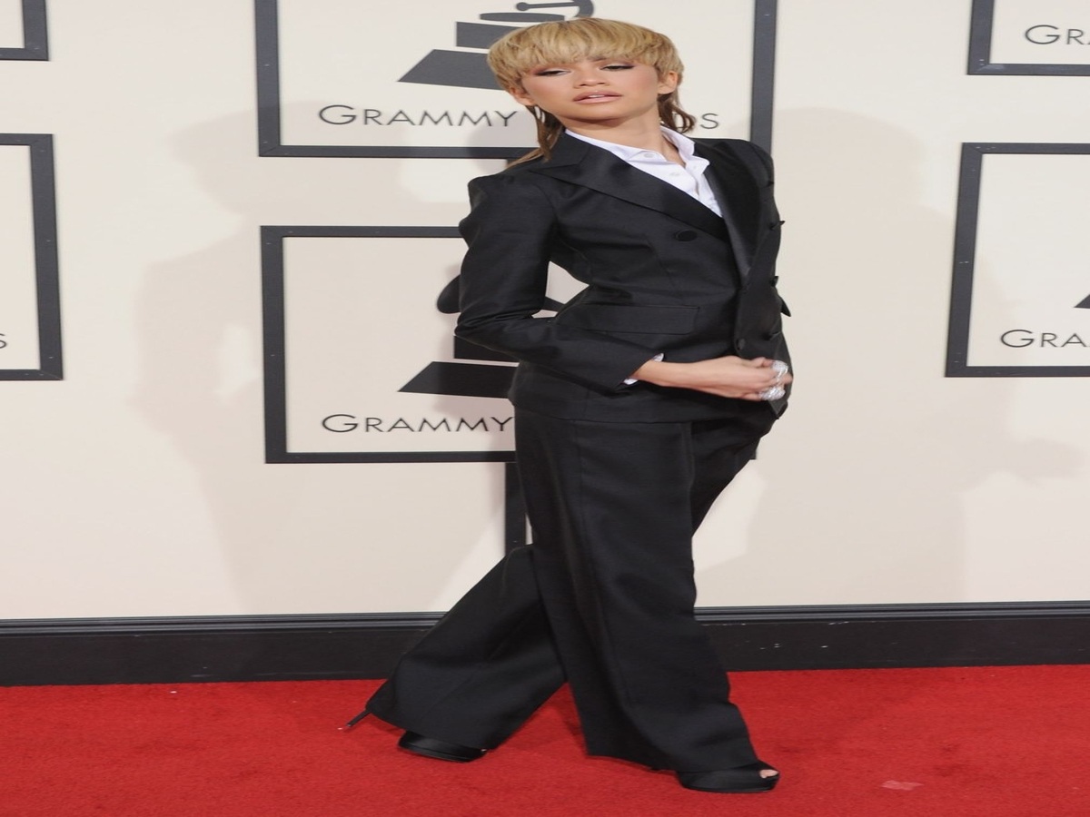 Zendaya on the red carpet at the 2016 Grammy Awards in a tailored suit and mullet haircut, embodying an edgy androgynous style.
