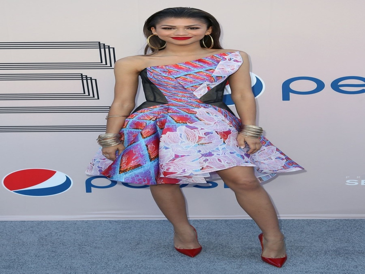 Zendaya attending the 2014 pre-BET Awards dinner in a colorful asymmetrical dress and red Christian Louboutin heels, showcasing her bold fashion sense.