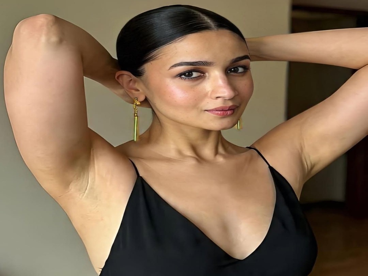 Alia Bhatt posing confidently in a stylish black outfit with elegant earrings, showcasing her fashion sense.