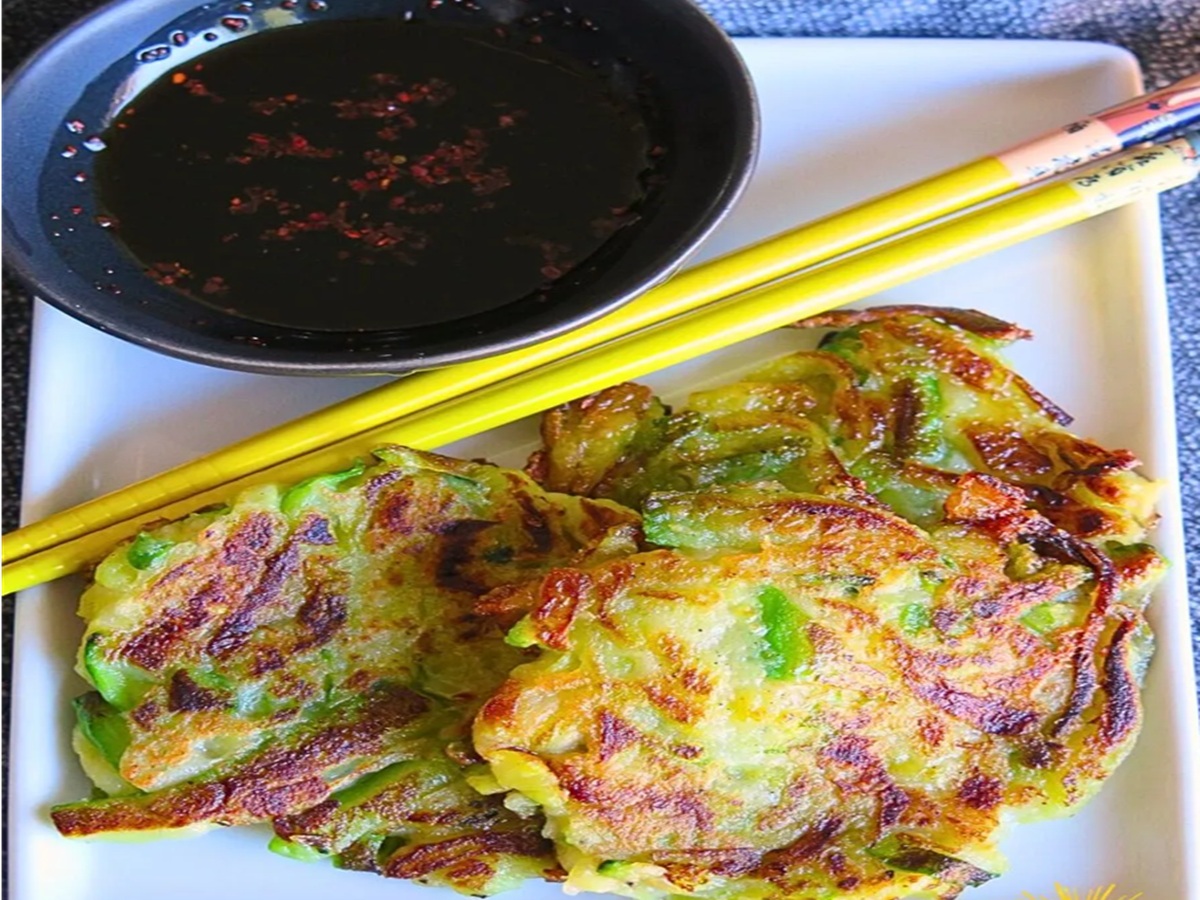 Korean zucchini pancakes (hobak buchim) stacked on a plate with dipping sauce on the side