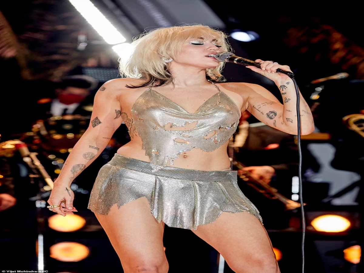 Miley Cyrus experiencing a wardrobe malfunction with her shredded silver top during a live performance, creating a memorable moment.