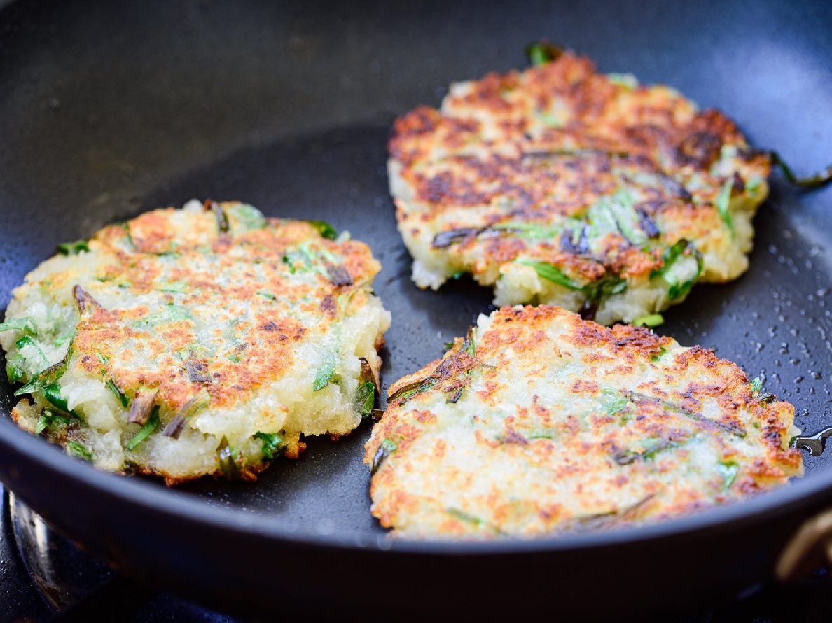 Golden brown Korean potato pancakes (gamjajeon) stacked on a plate with dipping sauce