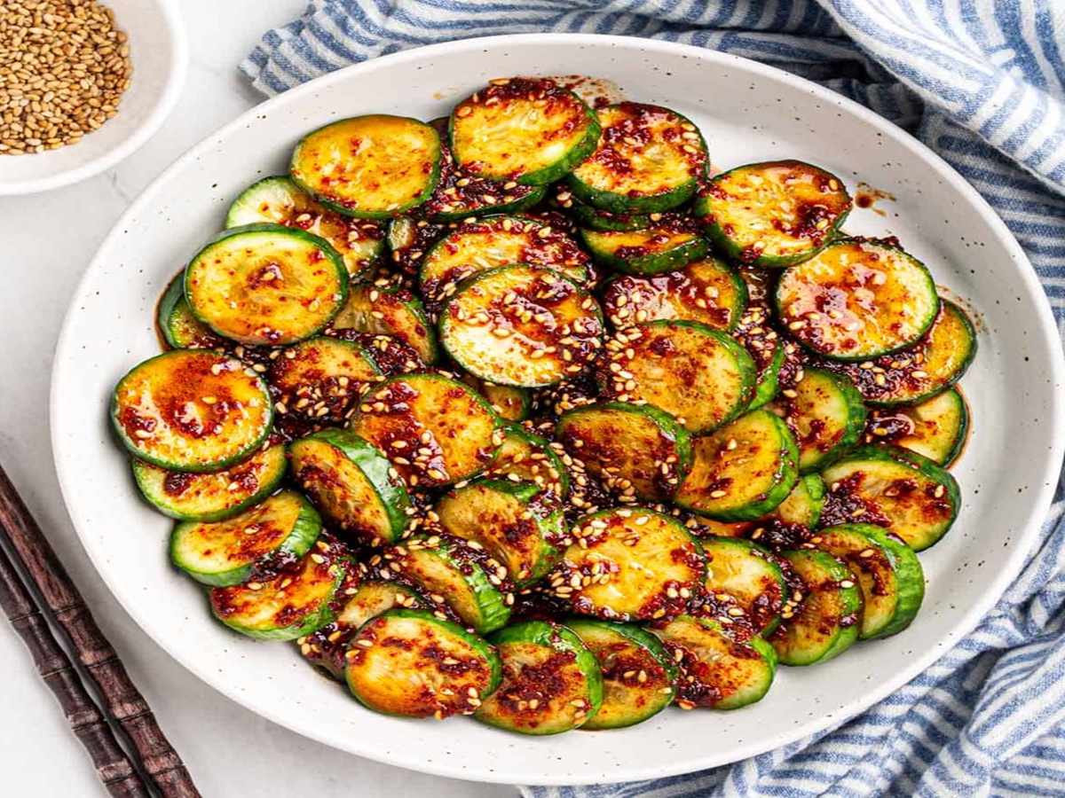 A plate of oi muchim, a Korean spicy cucumber salad, garnished with sesame seeds and sliced green onions