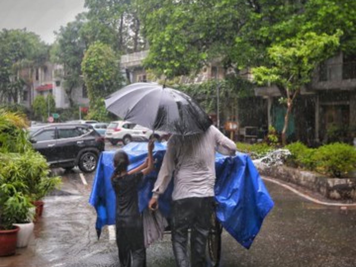 A person and a woman pushing a cart included in blue plastic even as sharing an umbrella at some point of heavy rain in a town region.