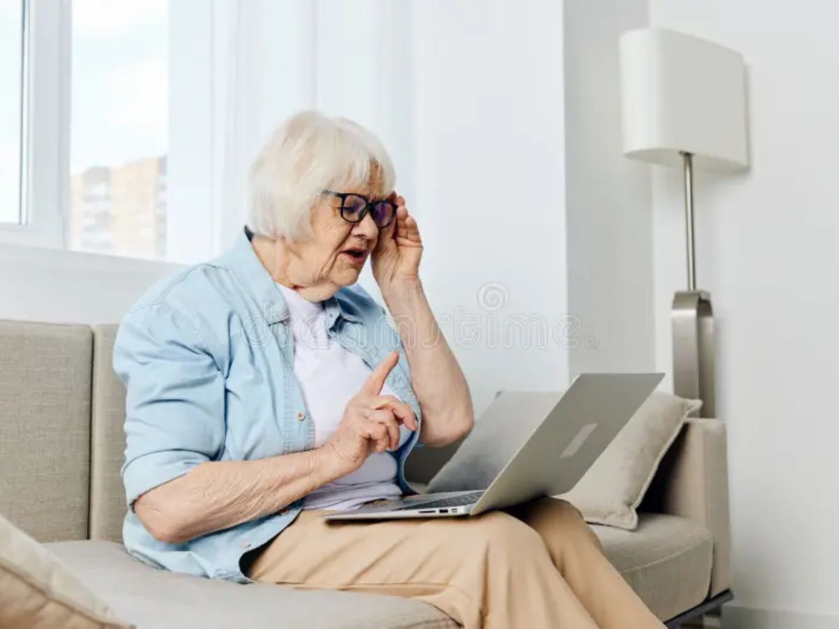 Elderly woman looking confused while holding a laptop
