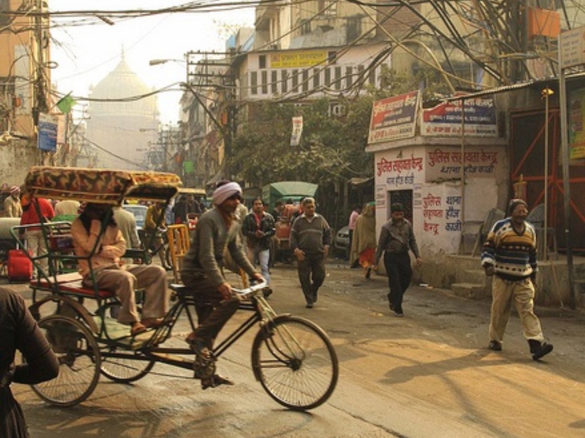 View from inside a moving rickshaw passing through a busy street.