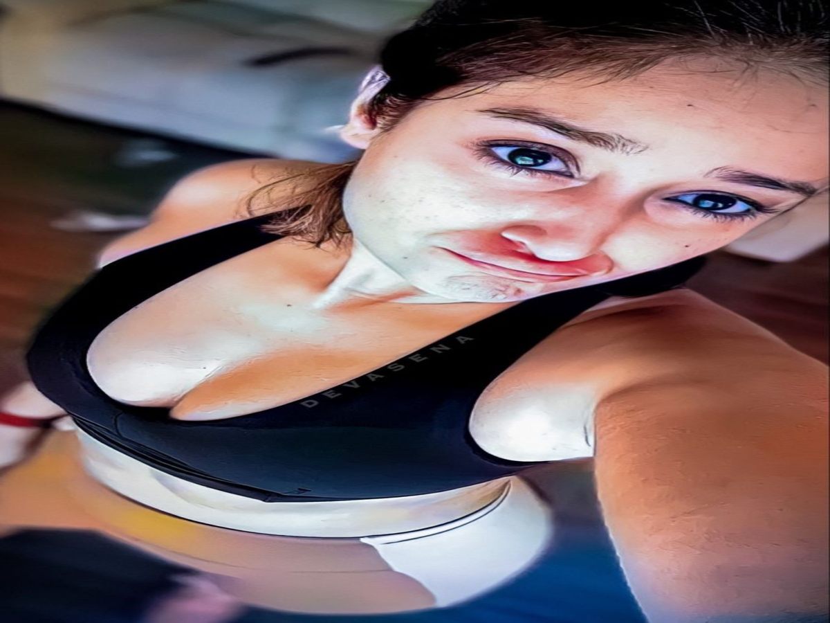 Woman in fitted black activewear, posing confidently indoors.