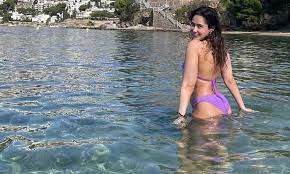 Pashmina in a lilac bikini wading through clear water