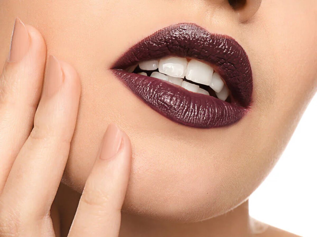 Dark plum lipstick with matte finish in dramatic lighting.