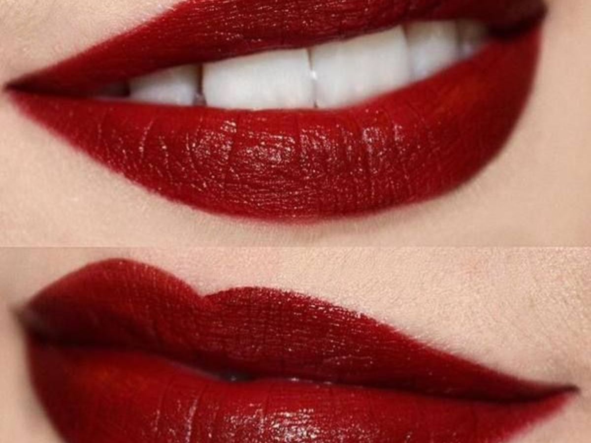 Close-up of lips wearing deep cherry red lipstick with glossy finish.