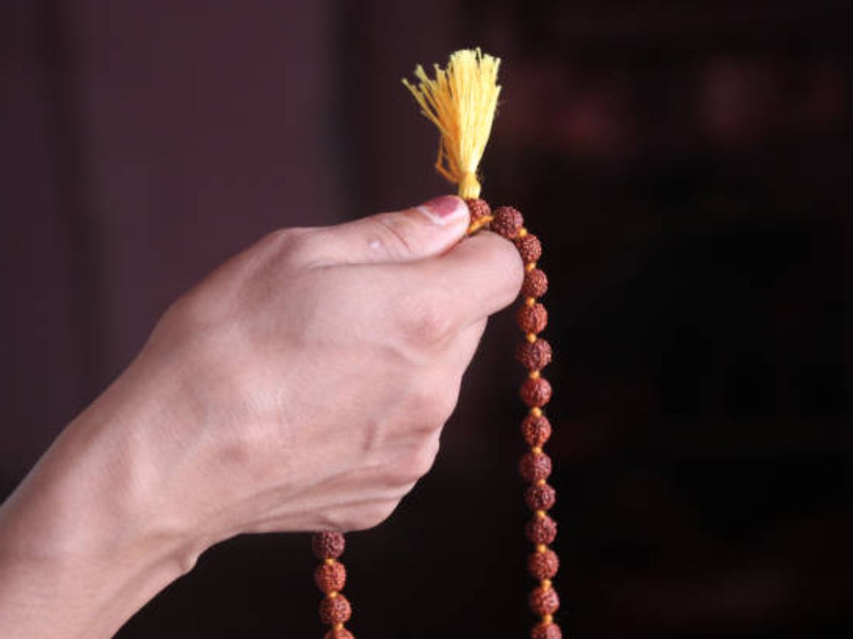 A person with Rudraksha chanting mantra near a Shiva idol.
