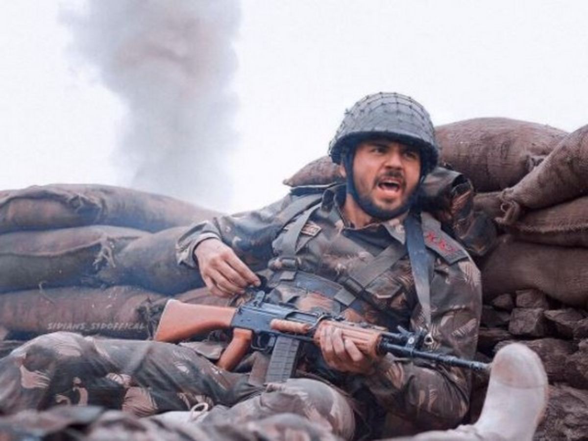 Sidharth Malhotra dressed as an Indian army officer in a battlefield scene, holding a rifle with smoke in the background, portraying Captain Vikram Batra in Shershaah.