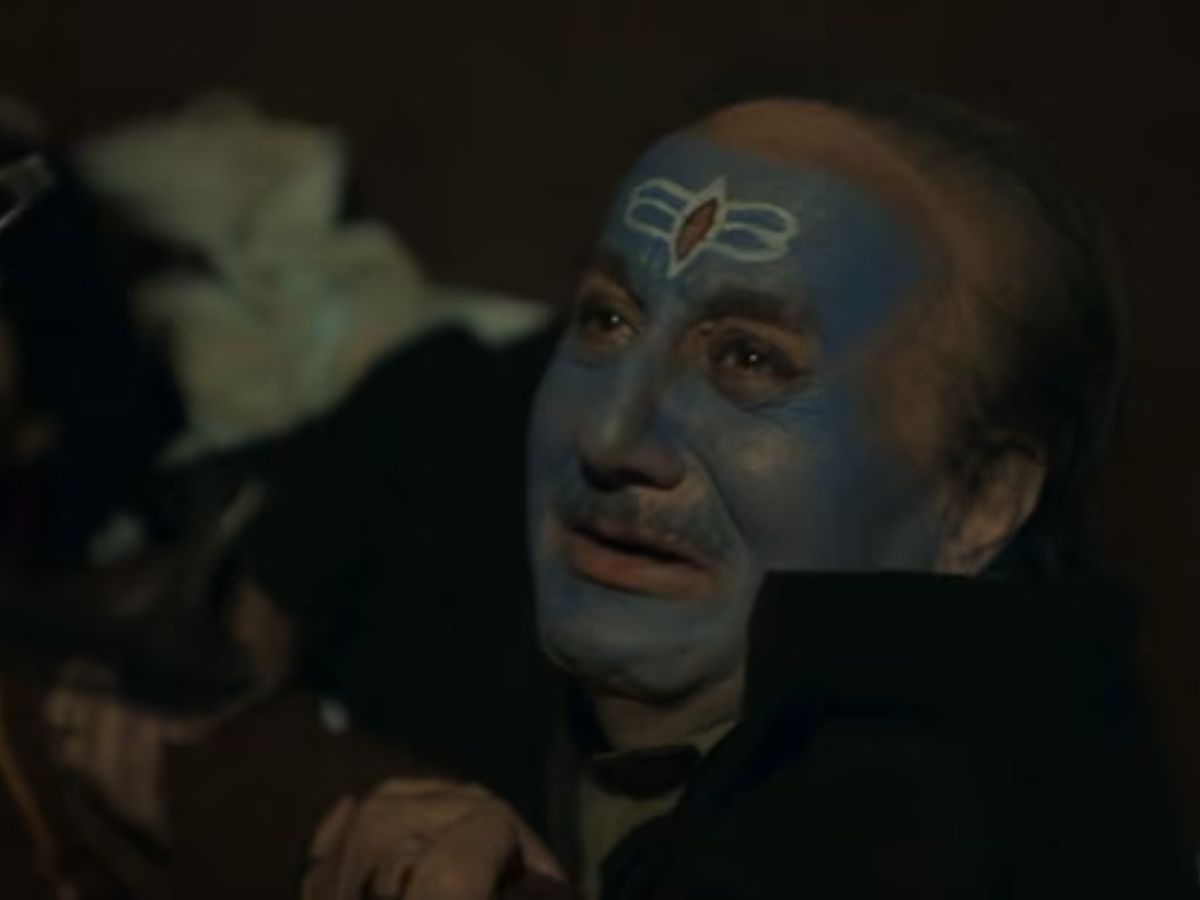 Anupam Kher with a painted blue face showing emotional pain, portraying a Kashmiri Pandit victim in a dark, intense scene from The Kashmir Files.