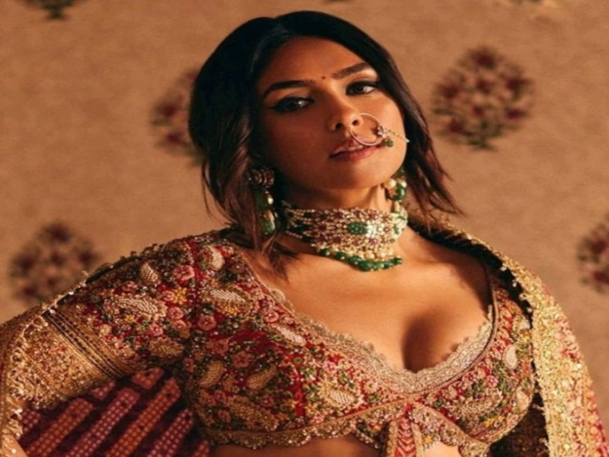 Model showcasing an intricately embroidered traditional outfit featuring a detailed blouse and flowing skirt.