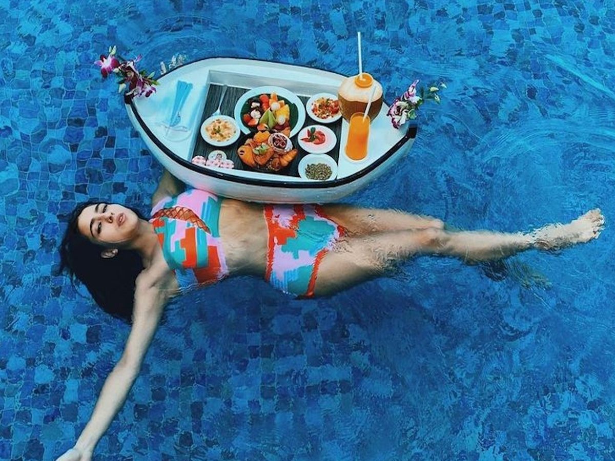Sara Ali Khan enjoying a relaxing moment in a vibrant bikini while lounging in a pool with a floating tray of food and drinks.