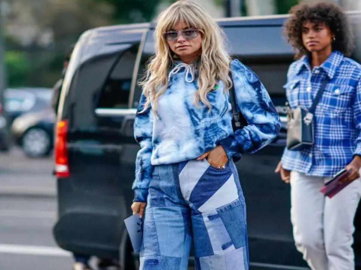 A pair of colorful patchwork jeans hanging on a clothing rack.