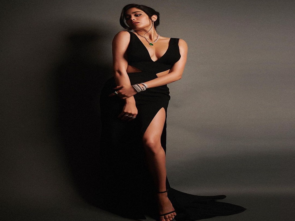 Janhvi Kapoor poses in a black cut-out dress with white piping details, showcasing a chic and glamorous look.